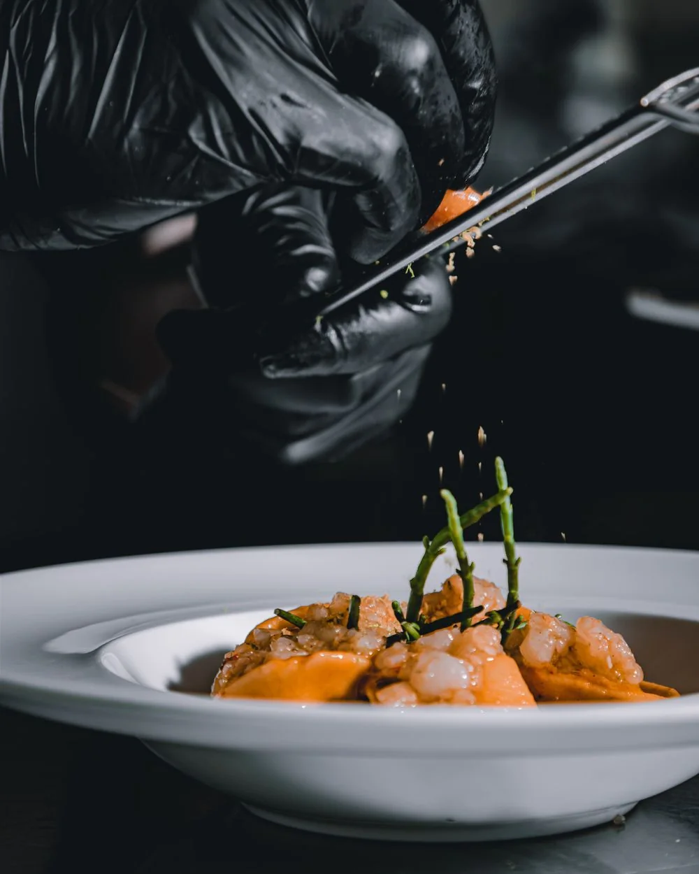 Chef seasoning fresh shellfish dish before service