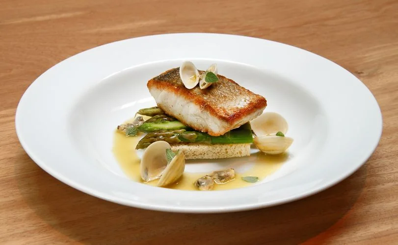 Meticulously arranged fish dish with tender clams and garden asparagus