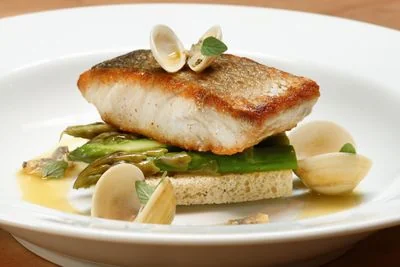 Artistic fish dish served with clams and asparagus