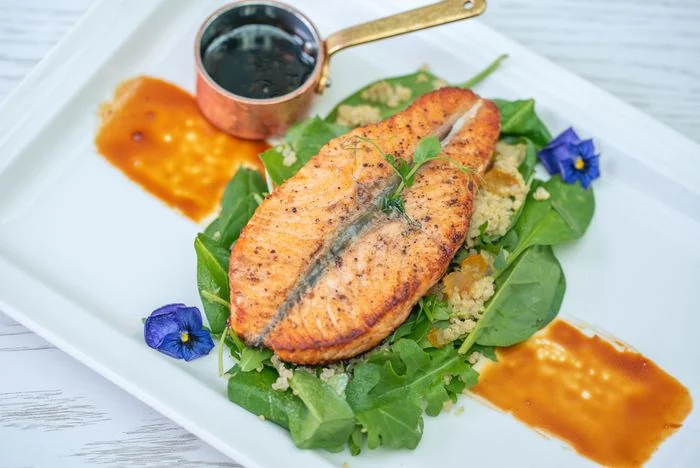 Pan-seared Canadian salmon fillet garnished with seasonal vegetables and emulsion
