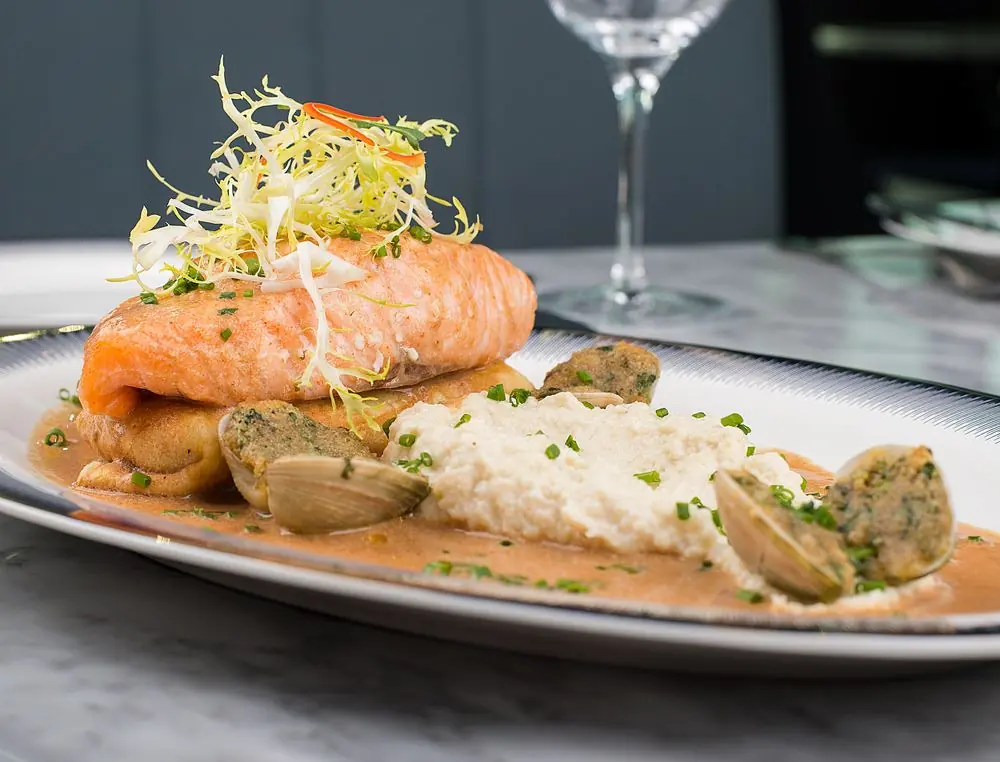 Seared salmon fillet with poached shellfish and emulsion garnish